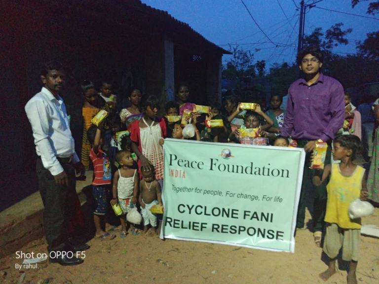 Peace Foundation volunteers and children with the Cyclone Fani Relief Response banner